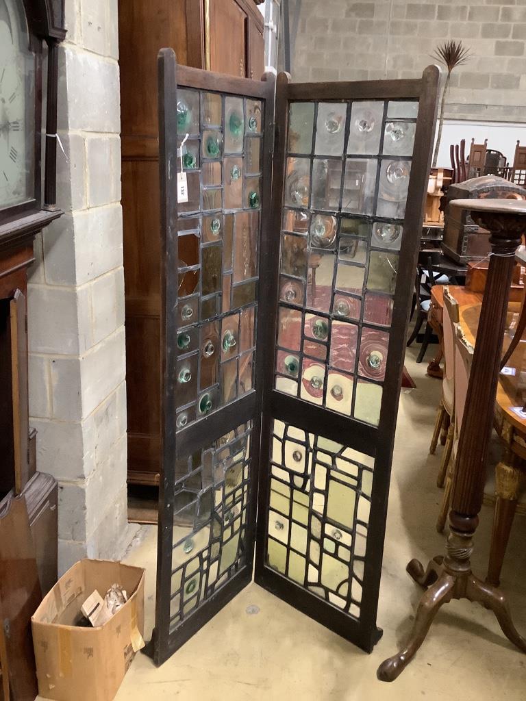 An early 20th century glazed oak two fold screen, each panel width 51cm, height 176cm